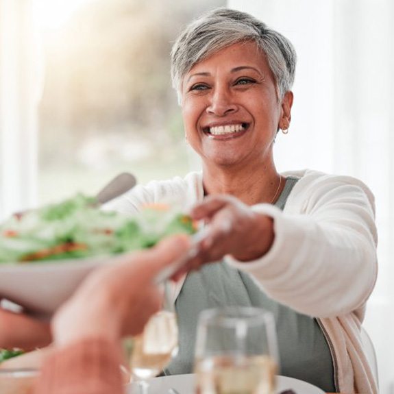 a woman smiling while eating a salad bowl