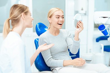 a patient checking her teeth with a mirror