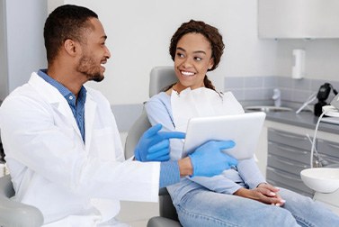 a dentist showing a patient a list on a tablet