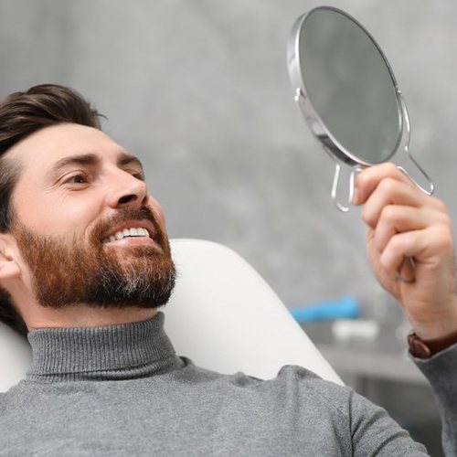 a patient checking his smile with a mirror