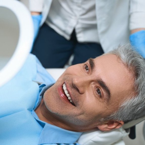 a patient checking his smile with a mirror